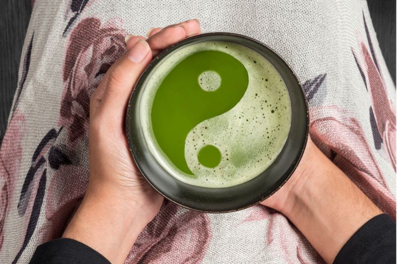 Una taza con líquido verde que muestra con la espuma el símbolo de Yin y Yang
